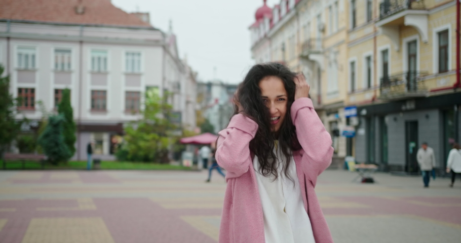 Delighted woman dancing in street and sending air kiss