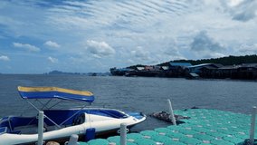 Speed boat at local village pier on dark teal sea water n calm ocean wave ripple on beautiful sunny blue sky with white cloud n fluffy cumulus cloudscape in summer sunlight, 4k b-roll footage video
