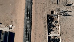  A high view of railway tracks in a desert landscape dilapidated buildings on side of track camera moving from high to low Aerial Video
