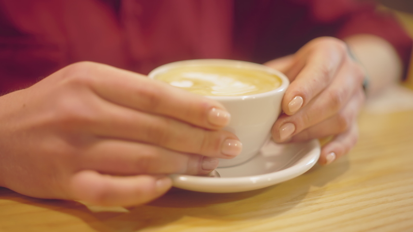 Slow-mo of beautiful young woman drinking cappuccino, coffee break relax
