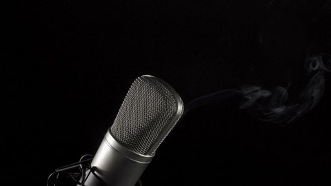 Smoking microphone. Professional audio recording equipment on an anti vibration stand, side lit.