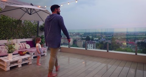 man opens sliding doors, going out on rooftop patio with cheerful baby girl