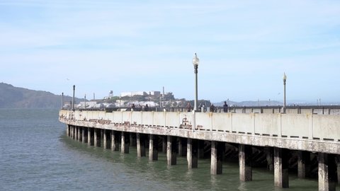 People walking by the pier and the Alcatraz Island in the background
