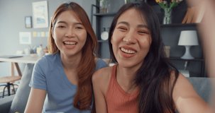 Teenager Asian women feeling happy smiling selfie and looking to camera while relax in living room at home. Cheerful Roommate ladies video call with friend and family, Lifestyle woman at home concept.