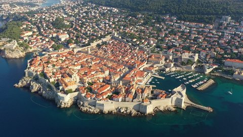 Aerial drone footage of the famous Dubrovnik medieval old town and harbor with its fortified walls and tower by the Adriatic sea in Croatia on a sunny summer. Shot with an orbit motion