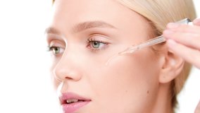 Big close-up shot of attractive European young woman applies face care serum on her cheek from dropper on white background | Face care serum advertising - Powered by Shutterstock - Get 15% off with code: PIKWIZARD15