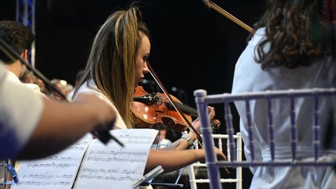 Sarajevo, BiH, 24 July 2021: Musician playing violin on festival with band on the stage. Female musician playing violin at live classical concert. Hands of musician playing instrument with orchestra.