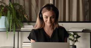 Female tutor teaches virtually via videocall, e coach concept. Company employee sit at workplace desk wear wireless headset use laptop provide helpful information through video conference application