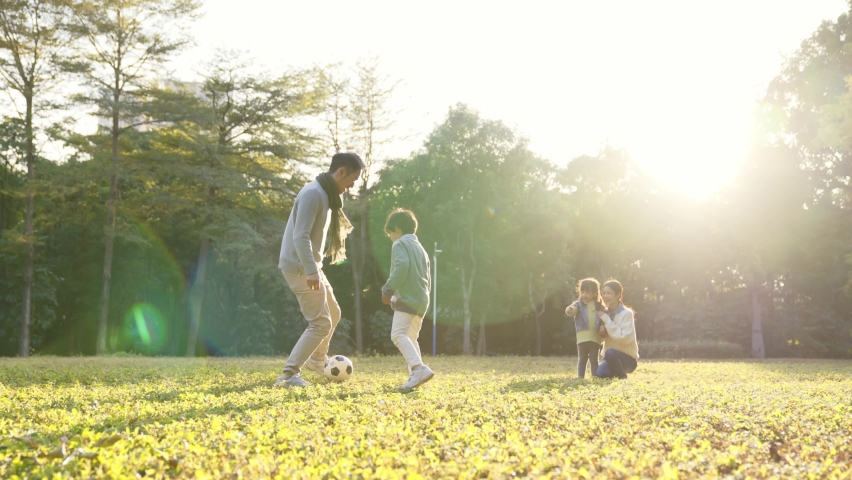asian father playing soccer with son outdoors in park Royalty-Free Stock Footage #1076468843