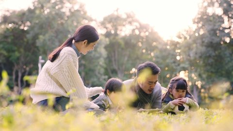 young asian couple with two children relaxing outdoors in park