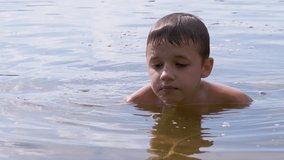 Active Child Playing with a Stick in River, in Water Creating Waves, Splashes. Wet boy enjoys playing with water drops. Teenager bathes in a pond. Water procedures, rest on nature. Zoom. Slow motion.