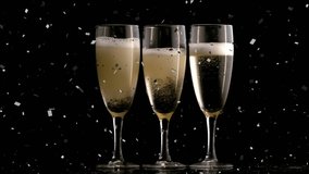 Animation of confetti falling over glasses of champagne. new years eve party and celebration concept digitally generated video.