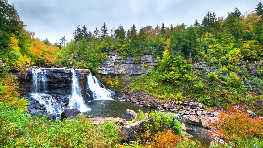 Point of view pov panning walking handheld shot of Blackwater Falls waterfall in state park, West Virginia at colorful autumn fall season with water flowing