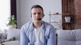 Smiling young Man in headphones looking at the camera, conversation with business client online. Male job applicant answering of questions at video call interview meeting. Distance education concept.