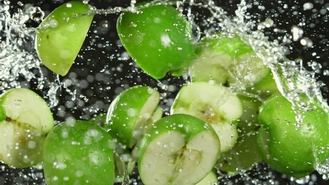 Super Slow Motion Shot of Flying Fresh Apple Slices and Water Side Splash Isolated on Black at 1000 fps.