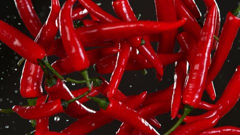 Super Slow Motion Shot of Flying Fresh Chilli Peppers Isolated on Black Background at 1000 fps.