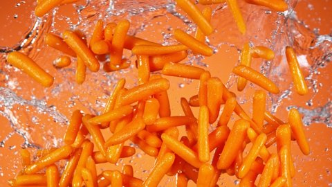 Super Slow Motion Shot of Flying Fresh Baby Carrots and Water Side Splash at 1000 fps.