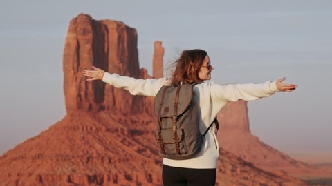 Happy woman enjoying incredible cinematic wild west landscape of Monument Valley at sunset, slow motion 4K footage. Feeling freedom and happiness, the best lifetime, drunk on life, elevated emotions