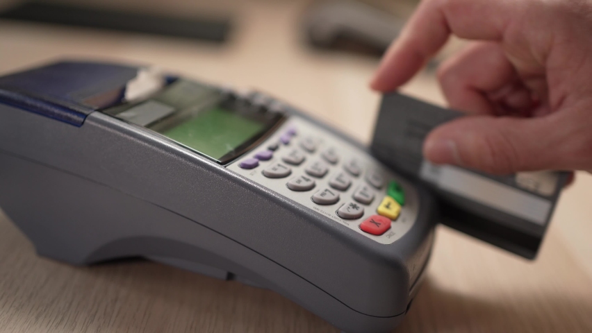 Camera rotating around a credit card terminal with a client swiping a plastic credit card and typing the code on the machine. Royalty-Free Stock Footage #1076485454