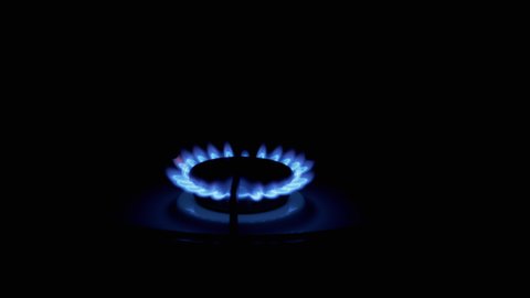 Turn on gas burner, blazing with a blue flame, at night in kitchen. Close-up. Light a gas stove by hand. Gas ignition. Natural gas is burning. Fire on stove. Heating room. 4K.