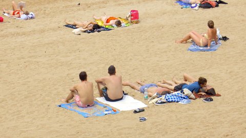 Biarritz, France - July 2021 : People sunbathing on beach towels Grande Plage beach in Biarritz, France