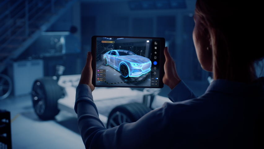 Automotive Engineer Working on Electric Car Chassis Platform, Using Tablet Computer with Augmented Reality 3D Software. Innovative Facility: Vehicle Frame with Wheels Becomes a VFX Virtual Model. | Shutterstock HD Video #1076498936