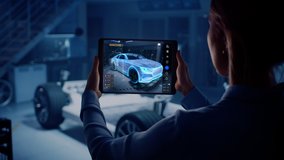 Automotive Engineer Working on Electric Car Chassis Platform, Using Tablet Computer with Augmented Reality 3D Software. Innovative Facility: Vehicle Frame with Wheels Becomes a VFX Virtual Model. - Powered by Shutterstock - Get 15% off with code: PIKWIZARD15