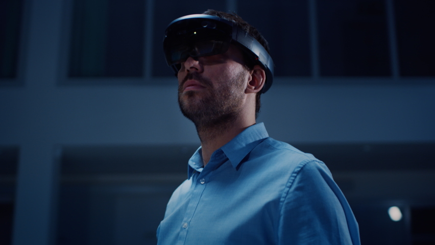 Young Adult Male Engineer Using Futuristic Augmented Reality Software Interface for Managing Work Projects. Specialist in Office Wearing Headset to Look at VFX Animation with Electric Car Concept. | Shutterstock HD Video #1076498948