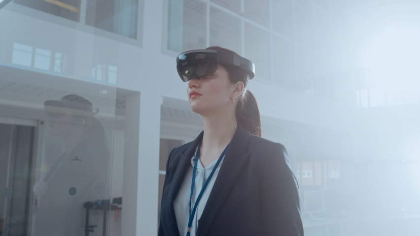 Young Adult Female Using Futuristic Augmented Reality Software Interface for Managing Business and Marketing Projects. Specialist in Office Wearing Headset to Look at VFX Animation with Financial Data Royalty-Free Stock Footage #1076498951