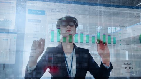 Young Adult Female Using Futuristic Augmented Reality Software Interface for Managing Business and Marketing Projects. Specialist in Office Wearing Headset to Look at VFX Animation with Financial Data