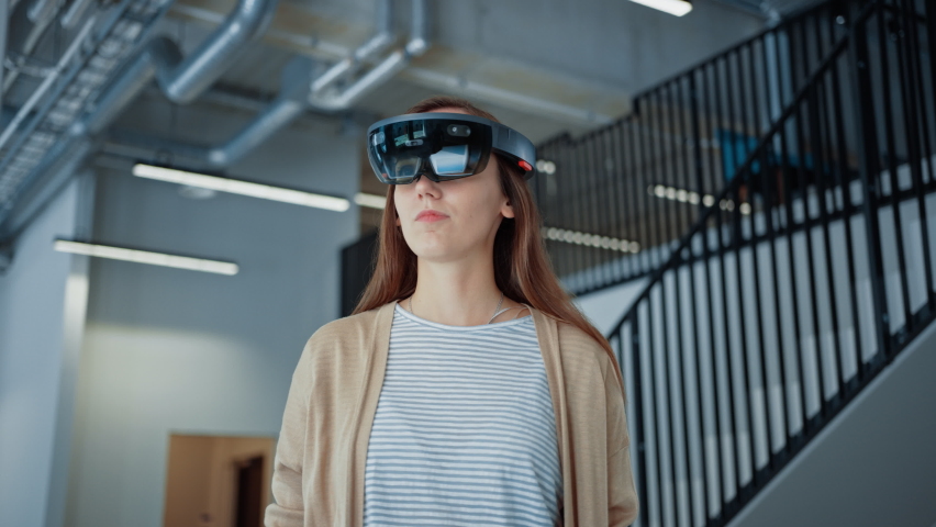 Young Adult Female Using Futuristic Augmented Reality Software Interface for Managing Business and Marketing Projects. Specialist in Office Wearing Headset to Look at VFX Animation with Financial Data Royalty-Free Stock Footage #1076498954