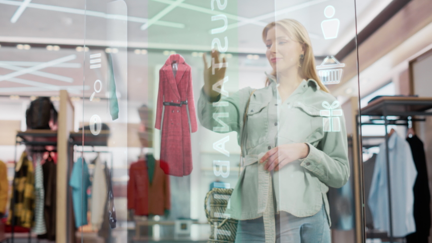Beautiful Female Customer Using 3D Augmented Reality Digital Interface in Modern Shopping Center. Shopper is Choosing Fashionable Bags, Stylish Garments in Clothing Store. Futuristic VFX UI Concept. | Shutterstock HD Video #1076499071