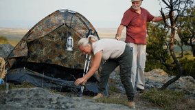Old happy retired couple is camping and preparing a campfire for an overnight stay in nature. Traveling in nature - Powered by Shutterstock - Get 15% off with code: PIKWIZARD15
