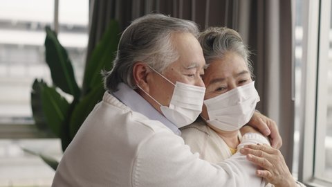 Elderly Asian couples wearing masks hug and encourage each other.