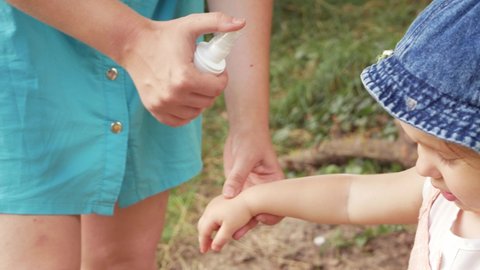 the mother treats the child with a spray for mosquitoes, insects, ticks, fleas. Picnic in the forest travel, protection, health care. Active lifestyle outdoor. hand