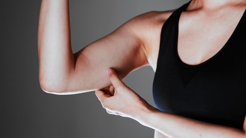 A woman touching her loose upper arm, diet image