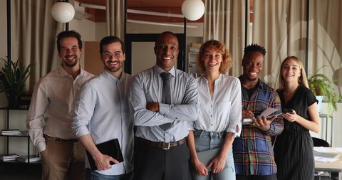 Six diverse multiracial professional business team portrait. Young company employees members led by African middle-aged boss standing in row in office pose on camera. Unity, career, equality concept
