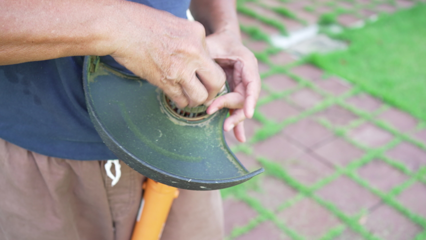 close up hand of gardener fixing lawn mower