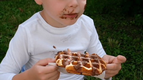 The child eating a Belgian waffle with a chocolate topping.top view. daily life dirty stain for wash and clean concept