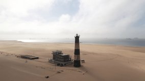 Flight over the oceanfront lighthouse at Sandwich Harbour in Namibia, Africa. UHD 4k drone video footage
