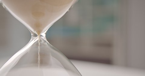 Hourglass or sandglass : Closeup view of golden sand falling down and pilling up in a sand clock or sand timer. Indicating passing of time. Each hourglass measures and has specific duration of time.