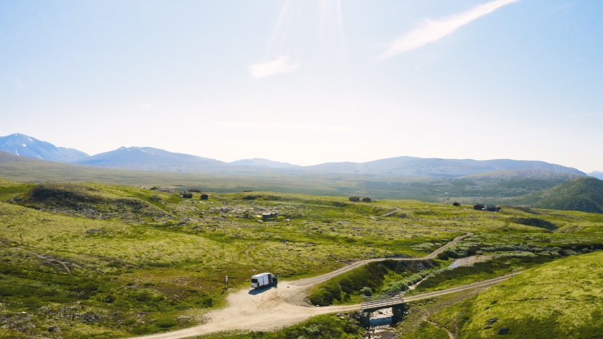 Vehicle At The Road Amidst The Green Meadow And Mountain Range In Rondane National Park In Norway. aerial, orbit