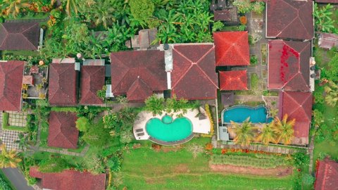 Aerial top view on traditional balinese architecture with traveler man enjoying summer vacation at swimming pool on Villa in Ubud. 4K Aerial UHD video clip. 