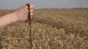 woman holding a christian cross walks in a wheat field 