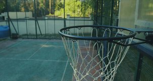 Basketball player cool young guy scoring hoop outdoor on court. Focus on basketball basket