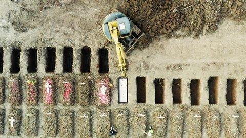 JAKARTA - Indonesia. July 23, 2021: Top down view of yellow excavator help to burial process Covid-19 victims at Rorotan graveyard. Shot in 4k resolution