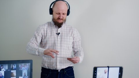 Learning English remotely online. A teacher with a beard, headphones and a microphone conducts a grammar lesson using flashcards to learn letters. remote learning