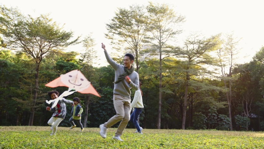 happy asian family having fun flying kite in park Royalty-Free Stock Footage #1076558123