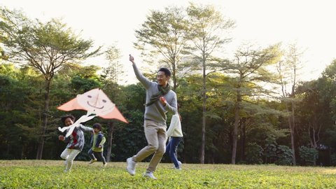 happy asian family having fun flying kite in park