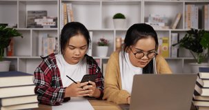 Happy twin asian girls using laptop and smartphone to learning online technology with her sister together. Social distance learning at home during quarantine. Education, learn from home, corona virus 